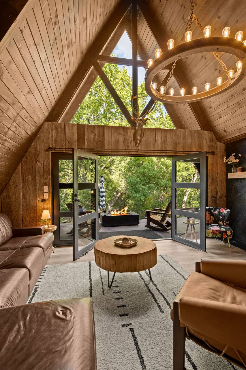 Living room straight on with doors open to green canopy — summer