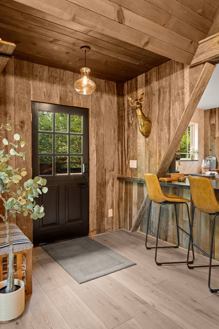 Entry with Dutch door, barstools, and green trees through glass — summer